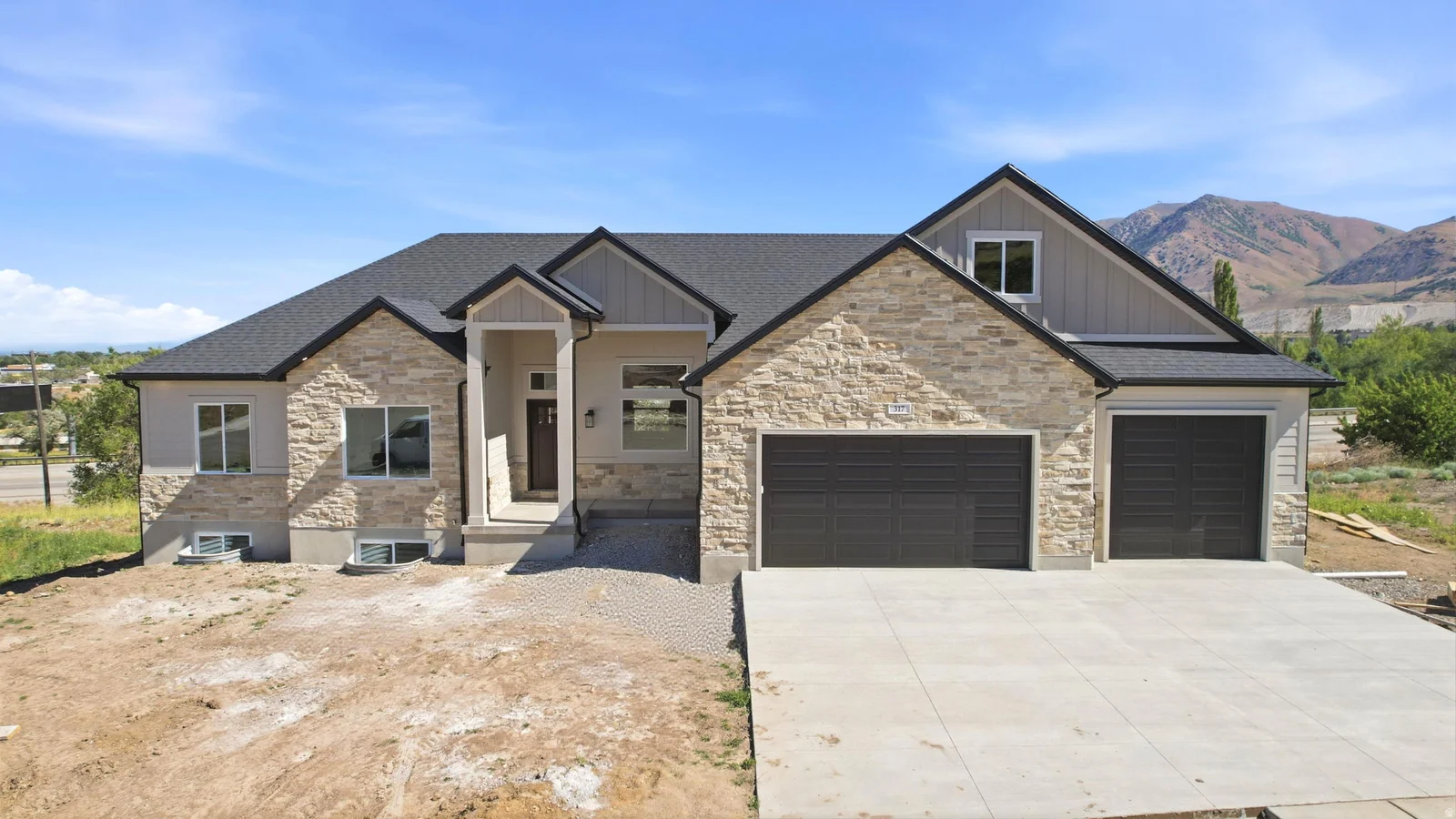 Contemporary residence featuring stone and siding exterior, dark shingles, an attached multi-car garage, and a concrete driveway